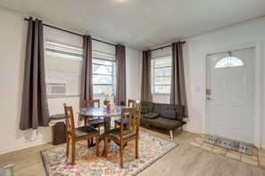 A dining area with a round table, chairs, and a sofa. There is a window with curtains, a door with a doormat, and a small trash bin. - 5 Mi to Ocean! Snowbird Haven in Lake Worth Beach (Lake Worth)