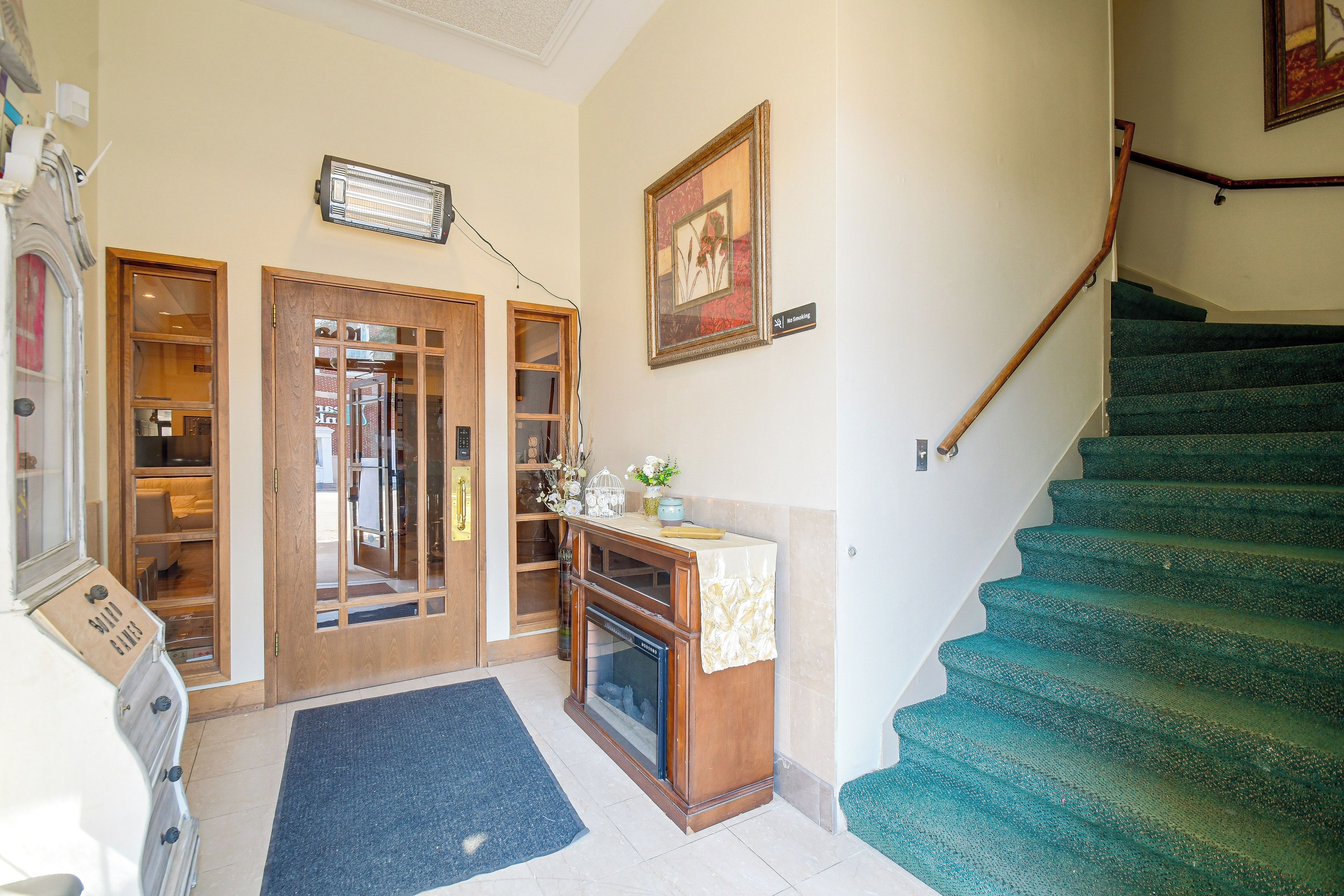 A hotel lobby with a staircase, a reception desk, and a door leading to a room.