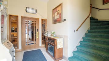 A hotel lobby with a staircase, a reception desk, and a door leading to a room.