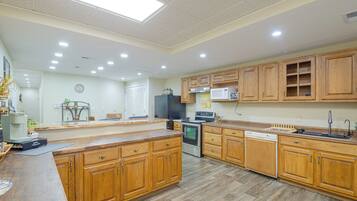 A modern kitchen with wooden cabinets, a central island, and built-in appliances.