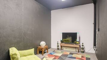 A room with a television on a wooden stand, a patterned rug, and a green sofa.