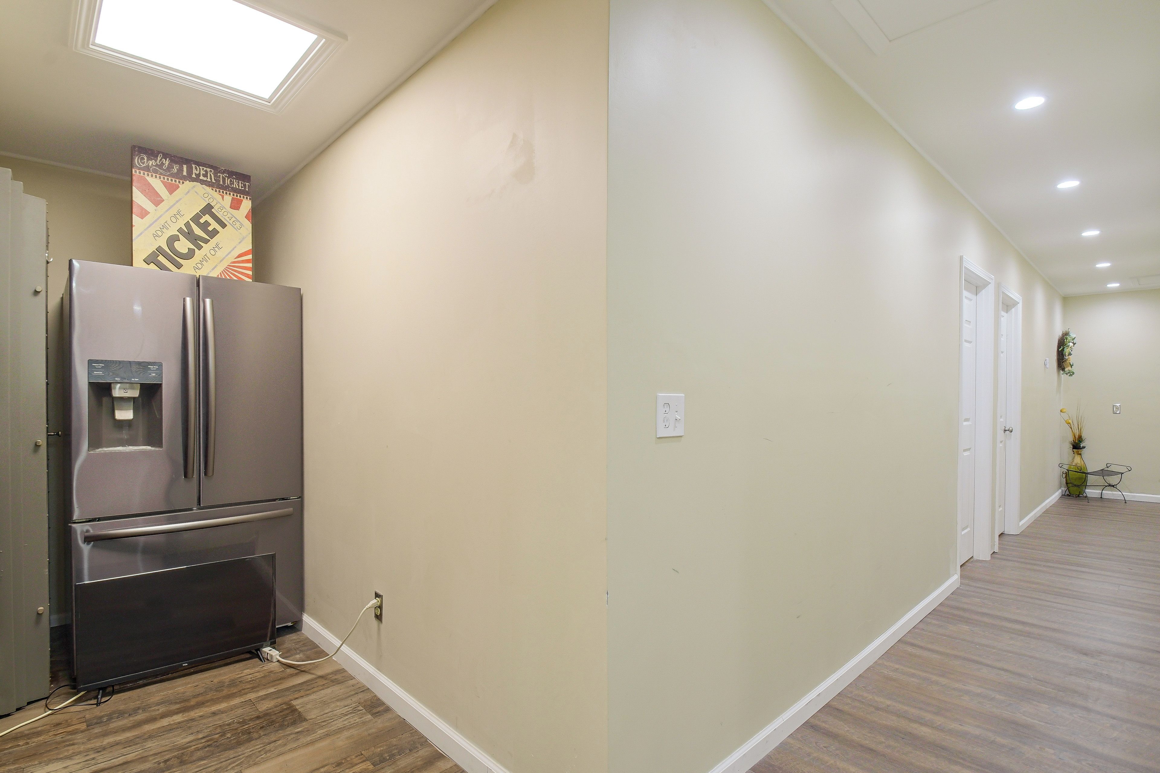 A hallway with a refrigerator, a water dispenser, and a sign above it.