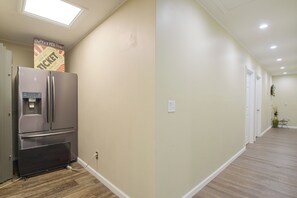 A hallway with a refrigerator, a water dispenser, and a sign above it.
