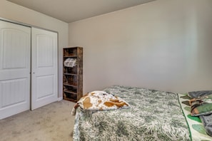 A bedroom with a bed, a wardrobe, and a shelving unit.