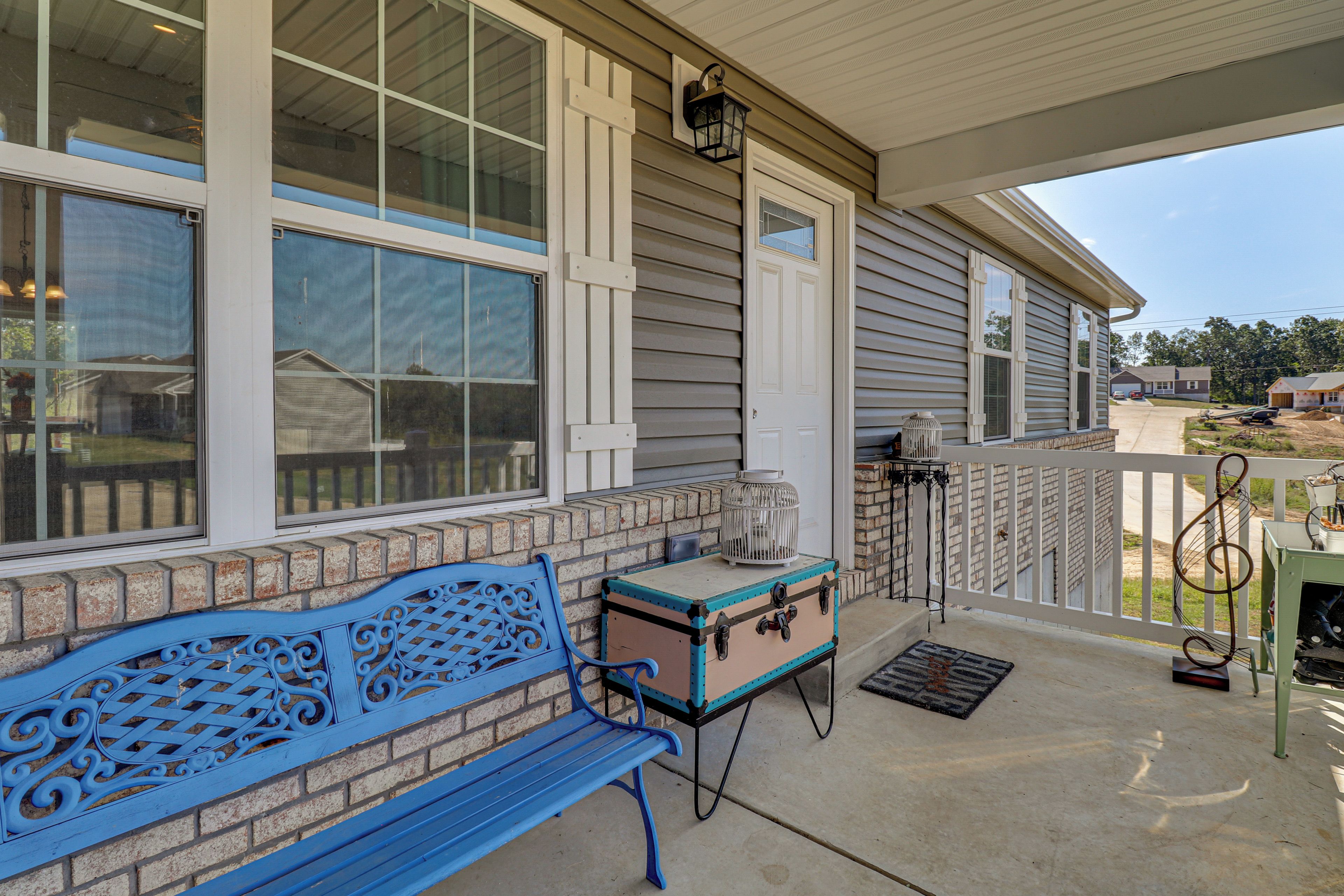A covered porch with a blue bench, a small table, and a lantern.