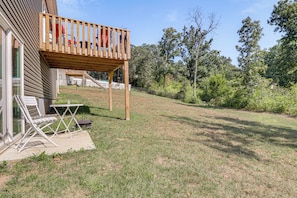 A backyard with a wooden deck, a grill, and a table with chairs.