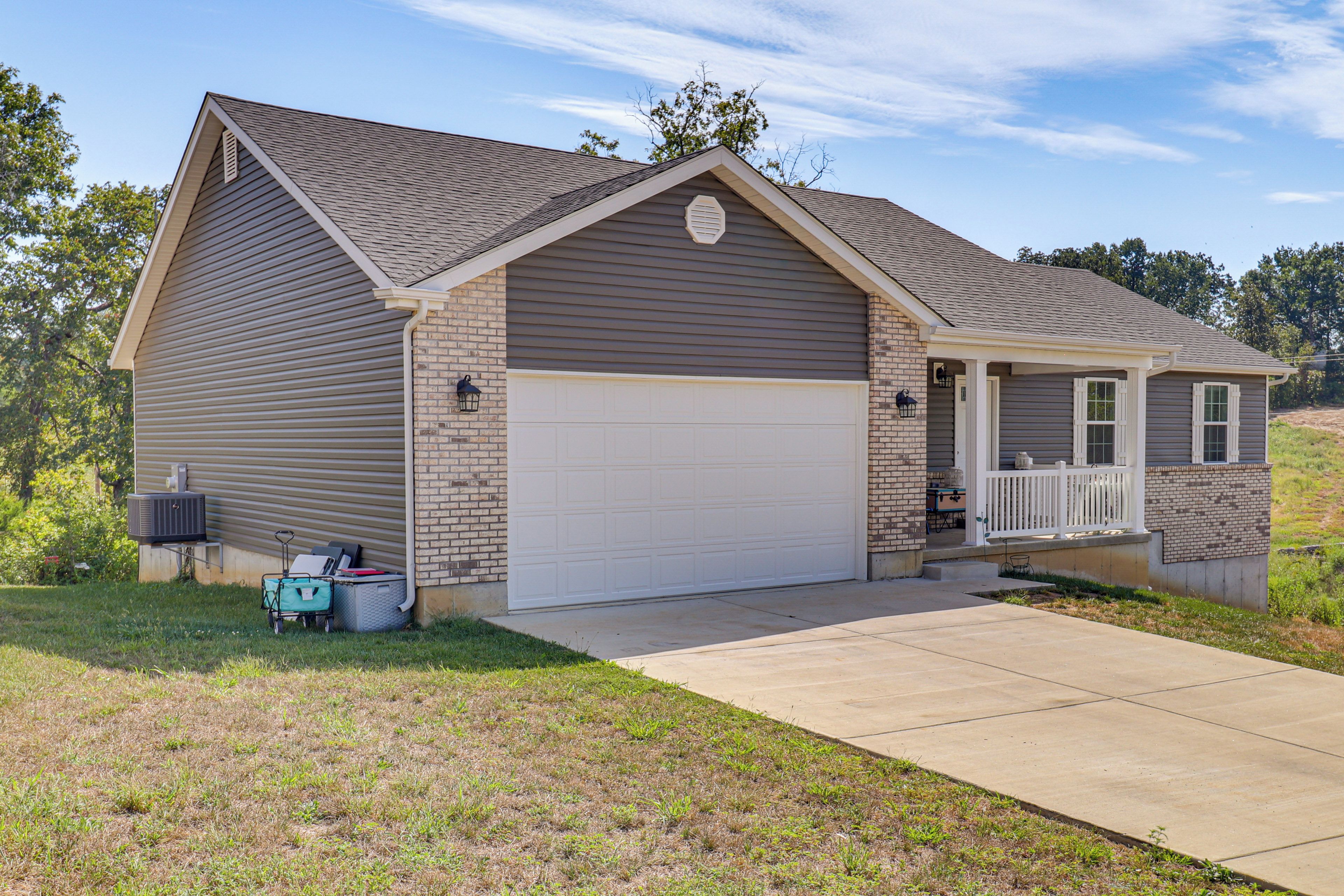 A single-story house with a garage, a covered porch, and a small outdoor seating area.