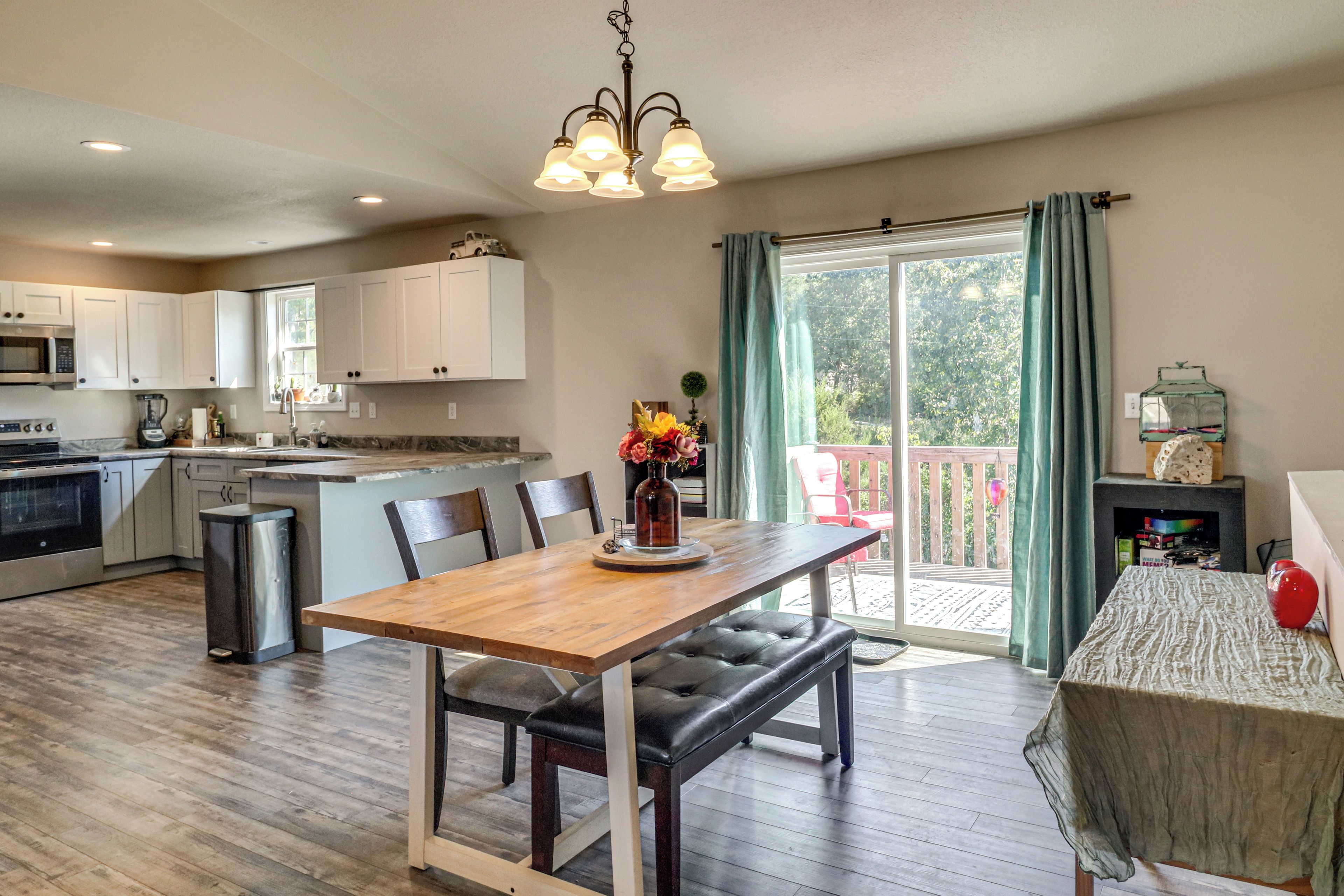 A modern kitchen with white cabinets, a central island, and a dining area with a wooden table and chairs.