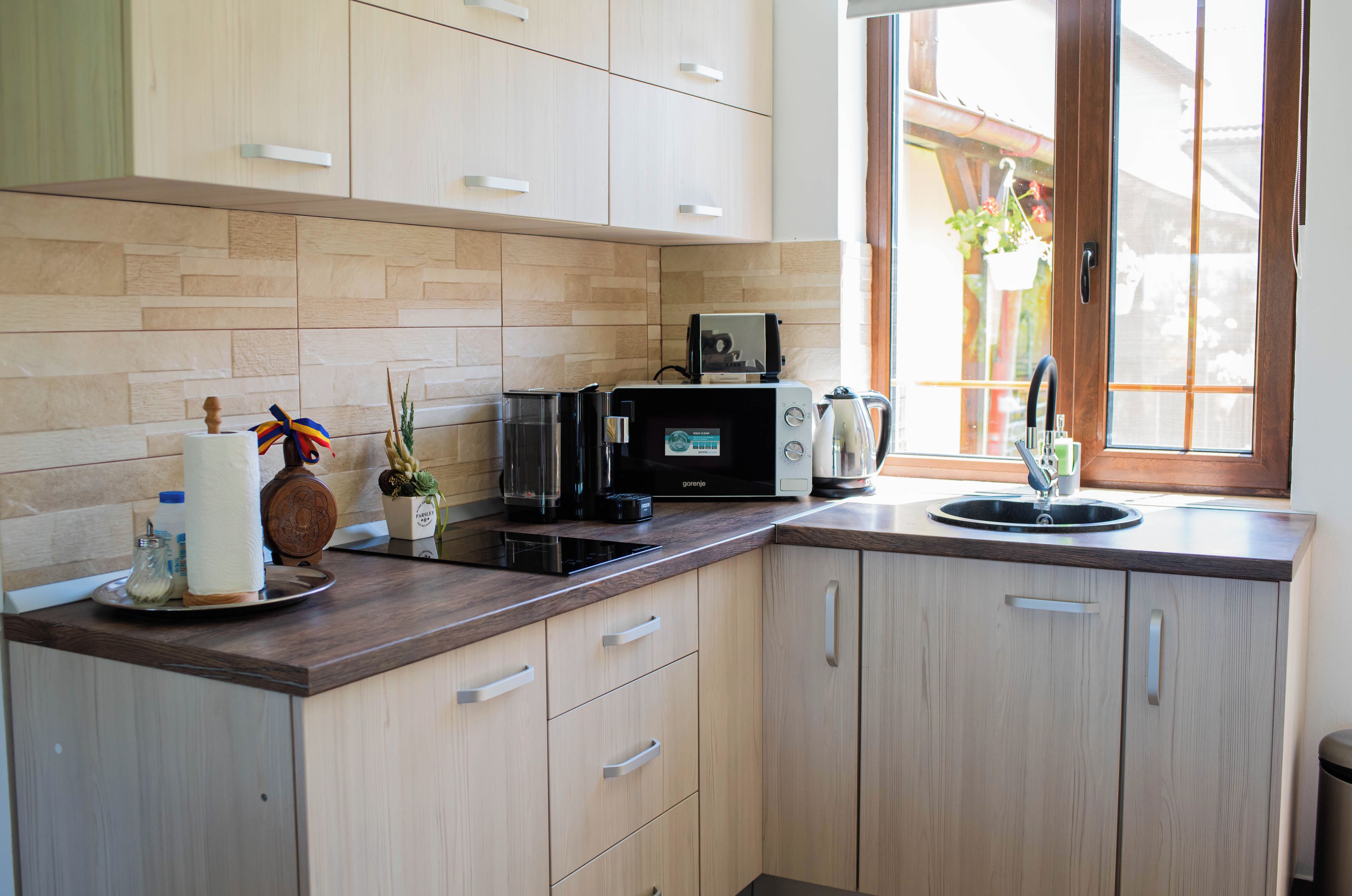 A modern kitchen with a built-in microwave, a coffee maker, and a sink.