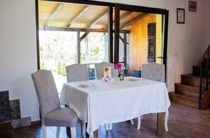 A dining area with a table set for two, chairs, a menu, and a vase with flowers.
