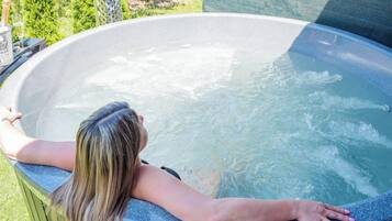 A person relaxing in a hot tub with a view of greenery.