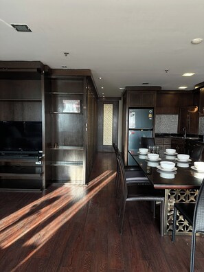 Una cocina moderna con muebles oscuros de madera, horno empotrado y comedor con mesa para cuatro.
