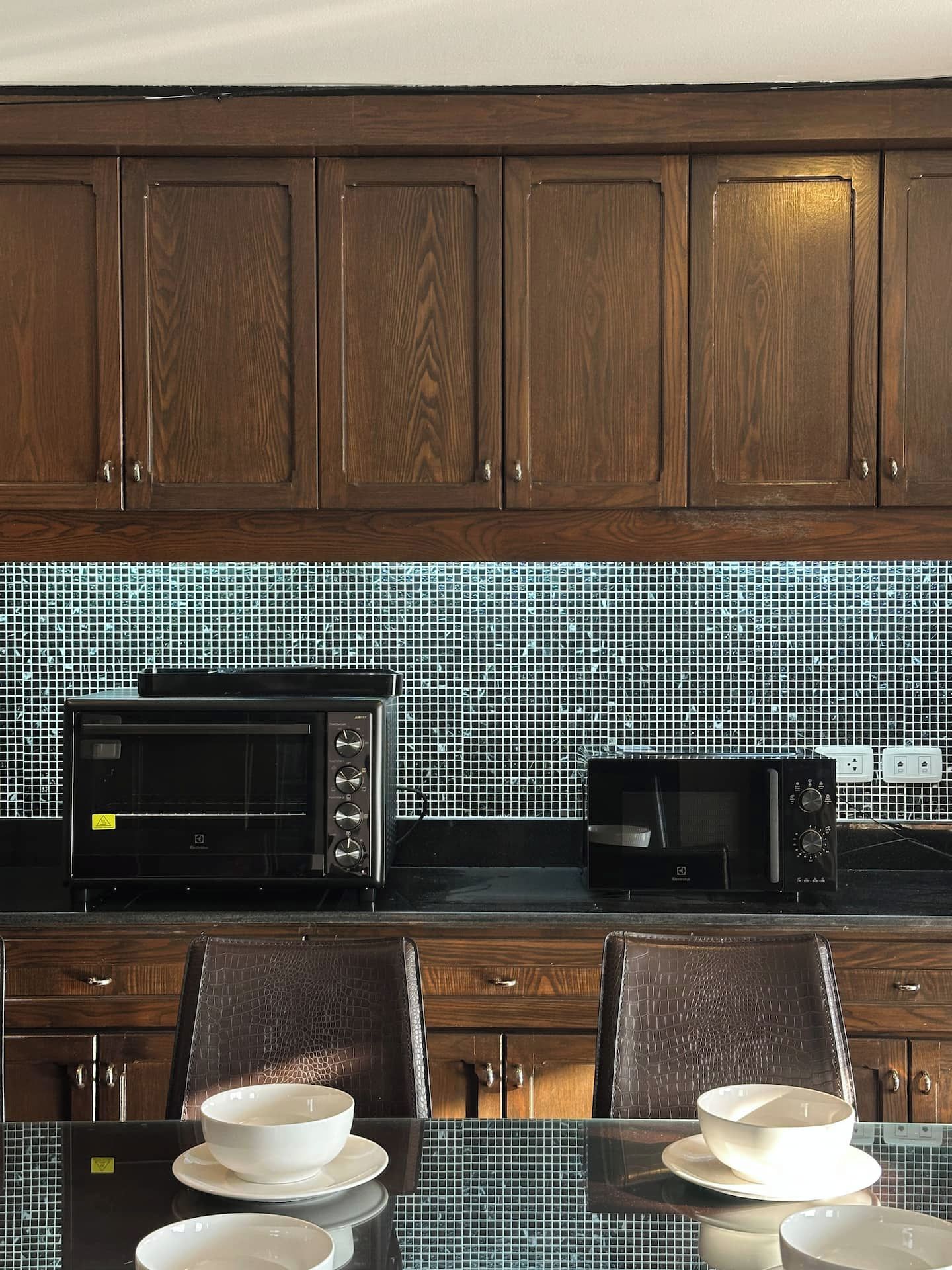 A kitchen with wooden cabinets, a tiled backsplash, and a dining table with chairs.