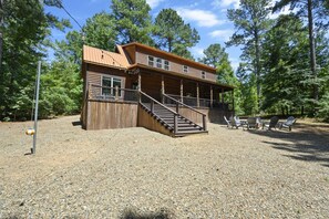 A two-story log cabin with a wooden deck and outdoor seating area. - Whispering Meadows|Fooseball|Firepit (Broken Bow)