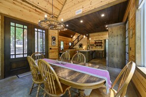 Ein Holzinterieur mit einem Esstisch, Stühlen und einer Chandelüster.
