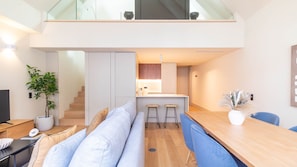 Ein modernes Interieur mit Essbereich, Küche und einer Treppe, die in einen oberen Bereich führt.