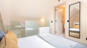 Una camera d'albergo con un letto, un ampio specchio, un termosifone e una porta che dà su un bagno.
