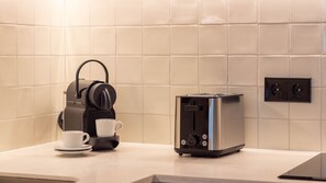 Eine Küchenzeile mit einer Kaffeemaschine, einem Toaster und einer Tasse auf der Arbeitsfläche.
