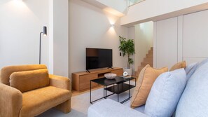 Ein modernes Wohnzimmer mit einer Couch, einem Couchtisch, einem Fernseher und einer Pflanze.