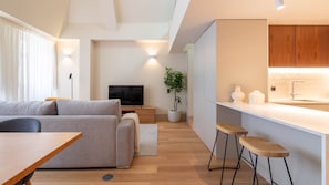 Ein zeitgemäßer Wohnbereich mit Sofa, Fernseher, Esstisch und Küchenzeile.
