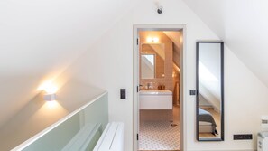 Un bagno moderno con doccia, WC e lavandino. C'è uno specchio a parete e un lampadario sopra lo specchio.
