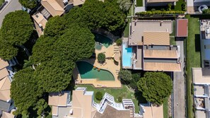 An aerial view of a residential area with a swimming pool, multiple buildings, and surrounding greenery. - Falésia Stylish 2BR W/Balcony & Pool by LovelyStay (Olhos de Água)