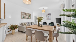 A modern living space with a dining area, sofa, and a television. - Falésia Stylish 2BR W/Balcony & Pool by LovelyStay (Olhos de Água)