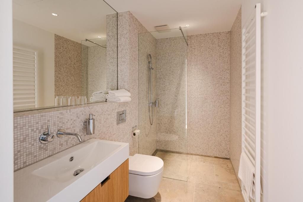 Une salle de bain moderne avec un grand miroir, une baignoire, des toilettes et une douche.