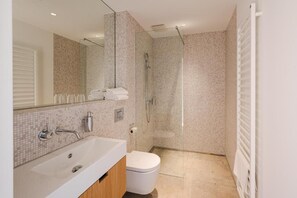 A modern bathroom with a large mirror, a bathtub, a toilet, and a shower. - das Ox (Münster)