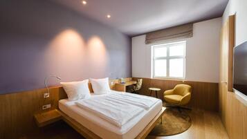 Une chambre d’hôtel moderne équipée d’un grand lit, d’un bureau, d’une chaise et d’un téléviseur.