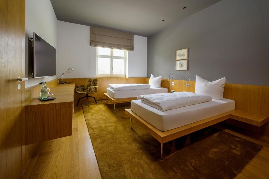 Une chambre d’hôtel avec deux lits, un bureau, une télévision et une fenêtre.