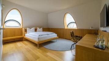 Un dormitorio moderno con cama, dos ventanas, un escritorio y una silla.