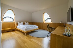 A modern bedroom with a bed, two windows, a desk, and a chair. - das Ox (Münster)
