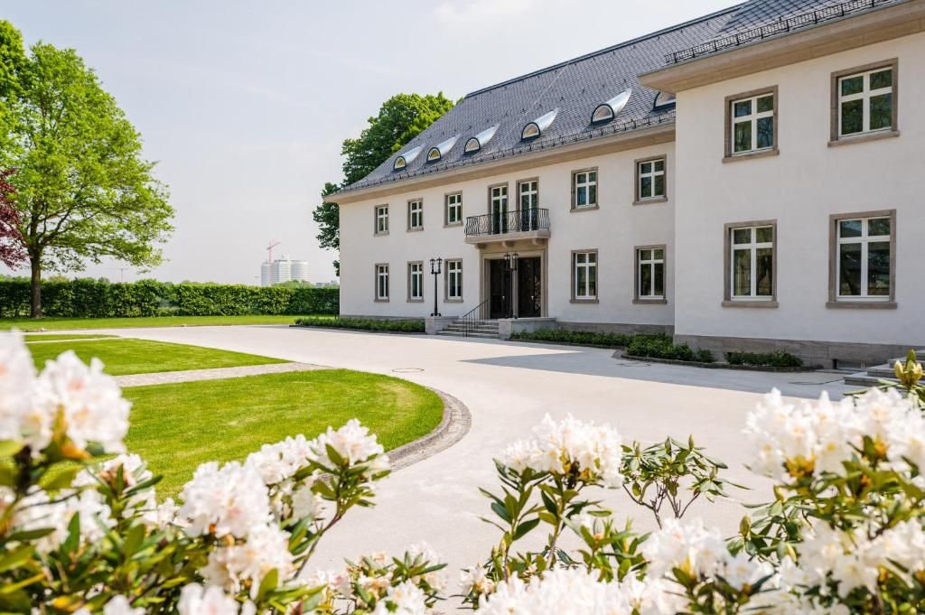 Un grand bâtiment blanc doté de nombreuses fenêtres et d’une entrée centrale.