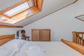 A bedroom with a skylight, wooden wardrobe, and a bed with white linens. - Beachfront apartment with balcony and parking, 1 min walk to beach (Split)