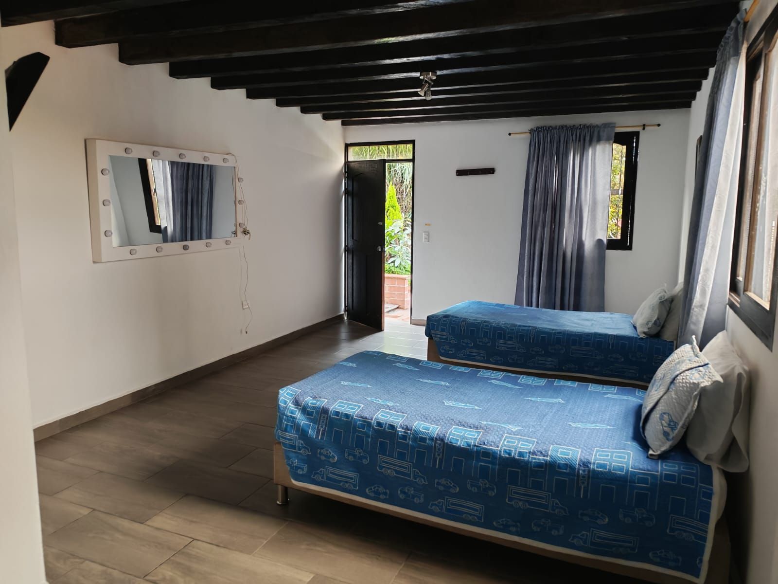 A room with two beds, a mirror, and a door leading outside.