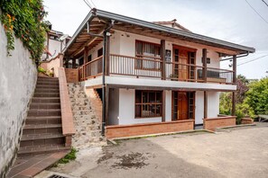 A two-story house with a balcony, a staircase, and a front door.