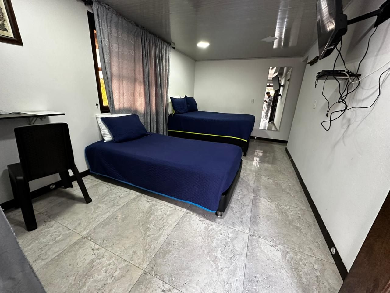 A room with two beds, a desk, and a chair.