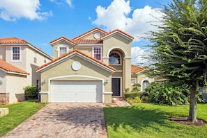 A residential house with a two-story design, a garage, and a well-maintained lawn.