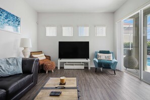 A modern living room with a flat-screen TV, a sofa, a coffee table, and a chair.
