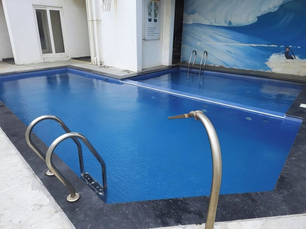 Une piscine dotée de rampes métalliques et d’une fresque représentant une vague sur le mur.