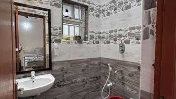 A bathroom with a skylight, a sink, a toilet, and a red bucket.