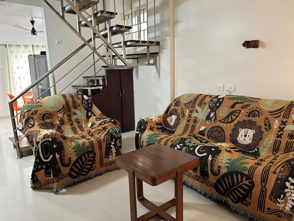 A living room with a sofa set, a coffee table, and a staircase.
