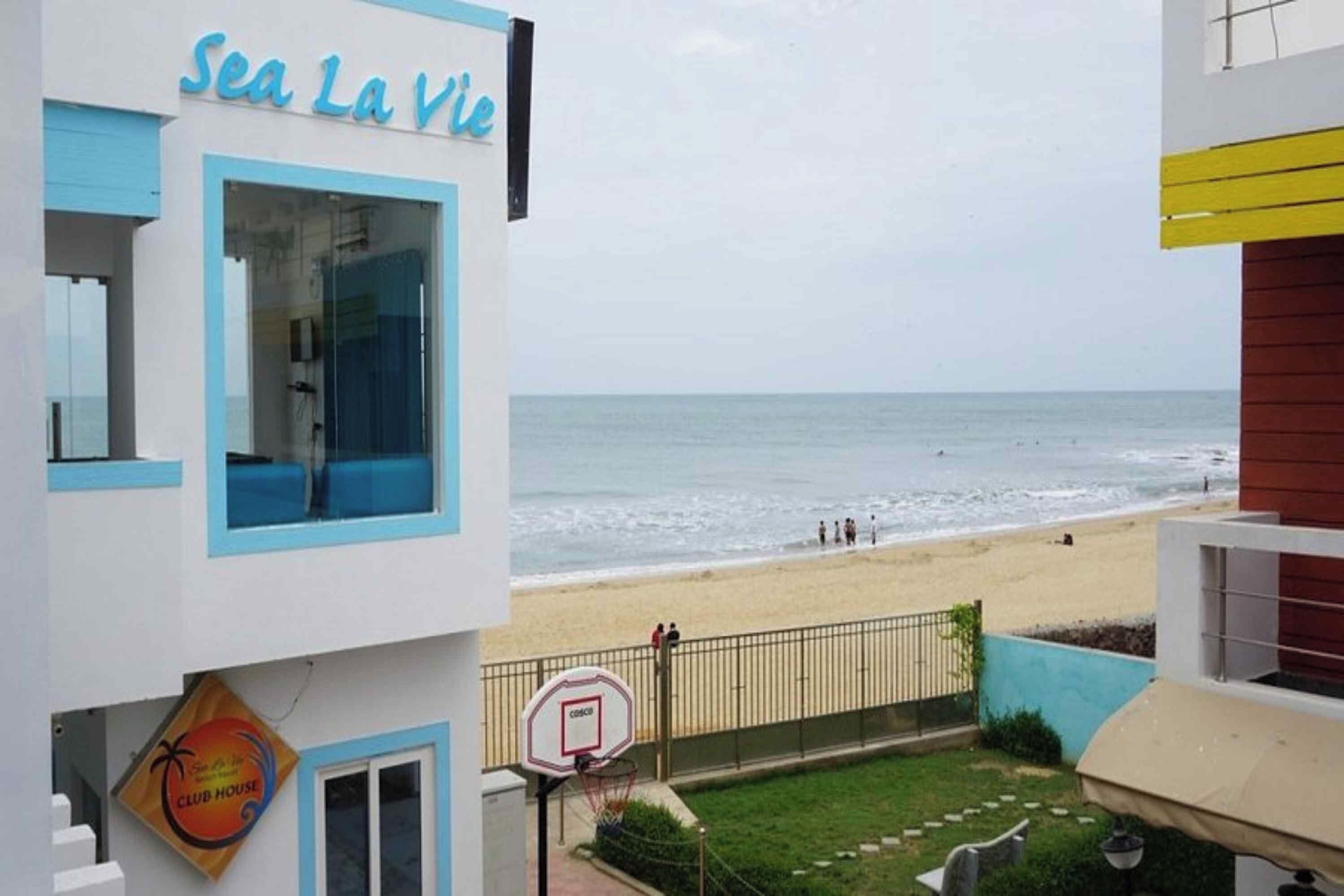 A building with a sign reading 'Sea La Vie' and a basketball court with a hoop.