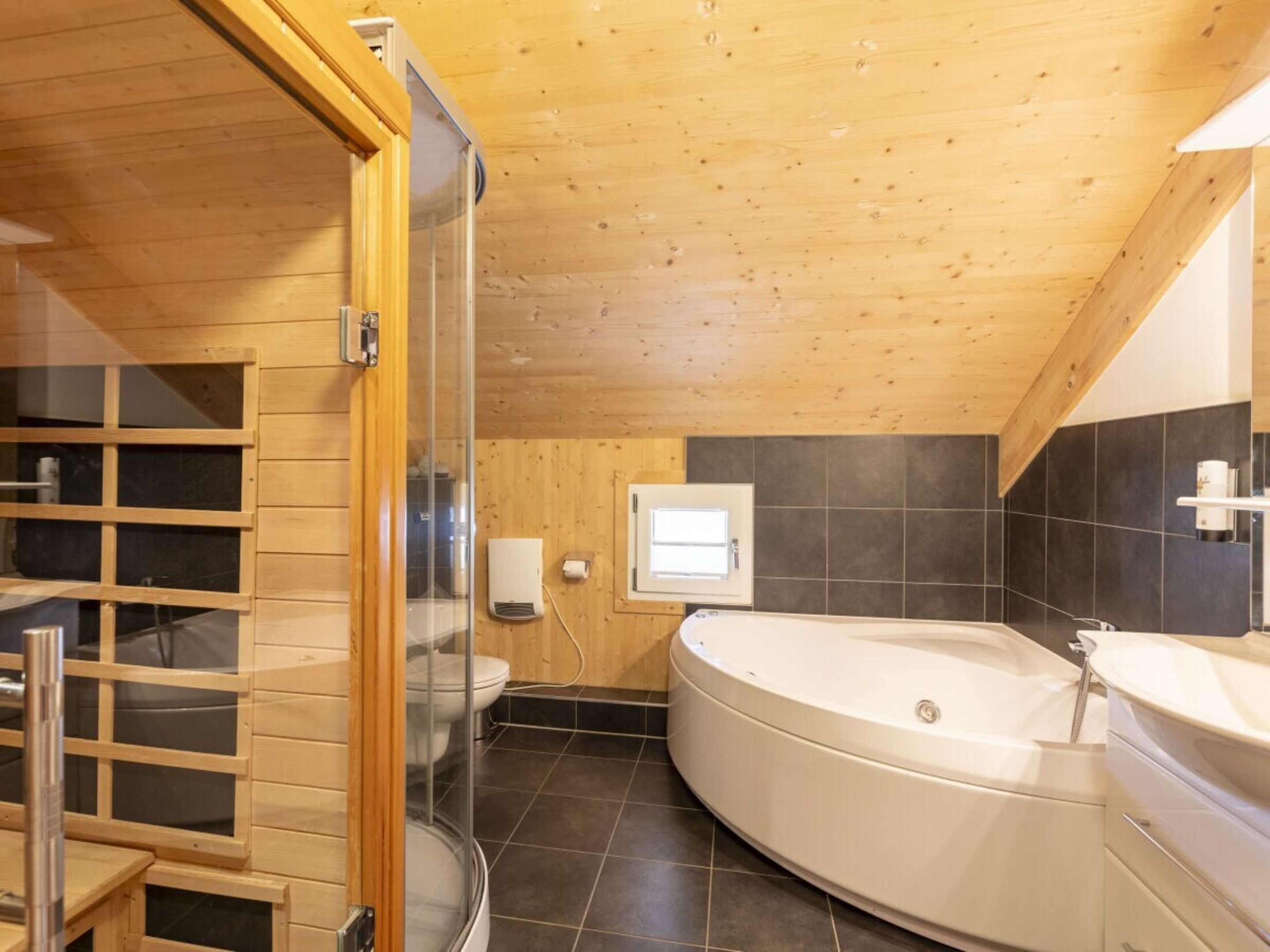 A modern bathroom with a freestanding bathtub, a glass shower enclosure, and a wooden ceiling.