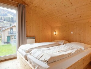 Ein Zimmer in einer Holzhütte mit einem Bett, einem Fenster und Blick auf ein Gebäude.