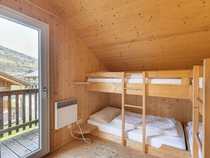 Eine Holzhütte mit Etagenbetten, einem Fenster und Blick auf eine Holzterrasse.