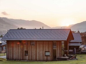 Ein rustikales Holzhaus mit einem geneigten Dach, einer Veranda mit Sitzgelegenheiten und Blick auf die Berge im Hintergrund.