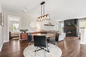 Ein modernes Wohnzimmer mit einem runden Esstisch, schwarzen Stühlen, einem Kamin und einem großen Fenster.