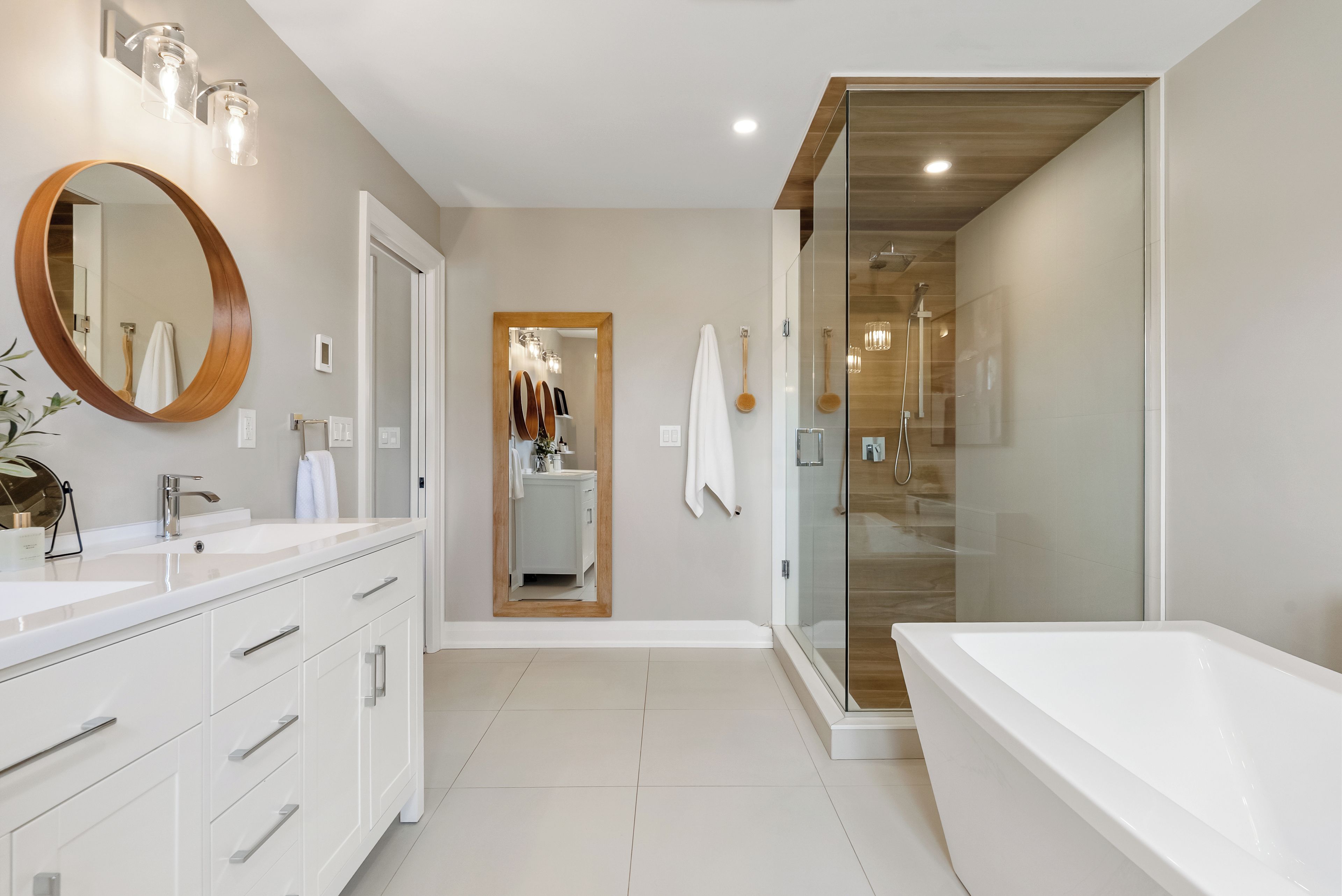 A modern bathroom with a large mirror, a bathtub, and a shower area.